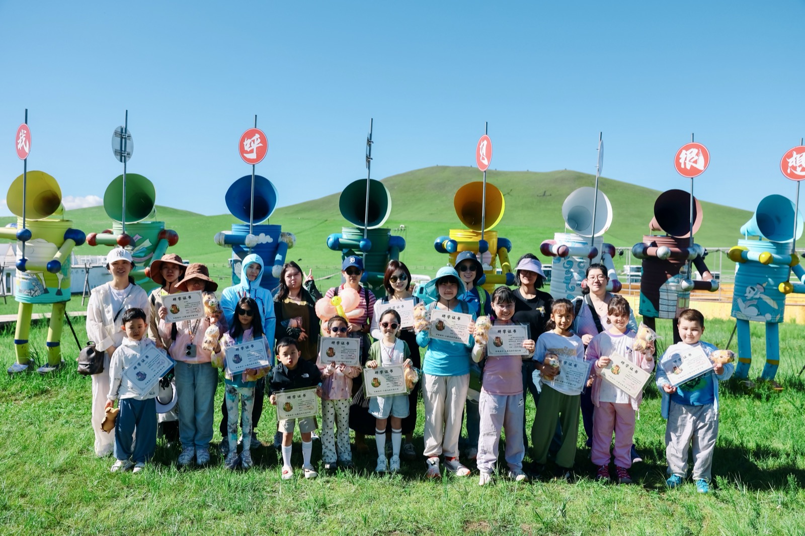 小蒙马夏令营结营仪式，家长和孩子们手持结营证书在营地合影